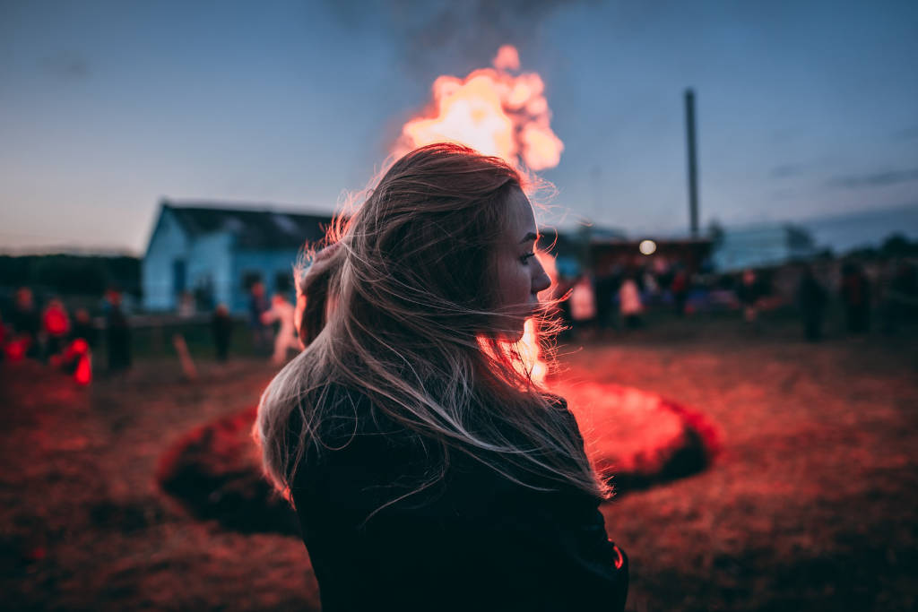 Chica joven delante de un fuego con la cabeza girada hacia la derecha