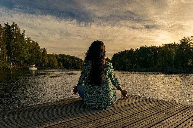 mujer meditando de cara a un río