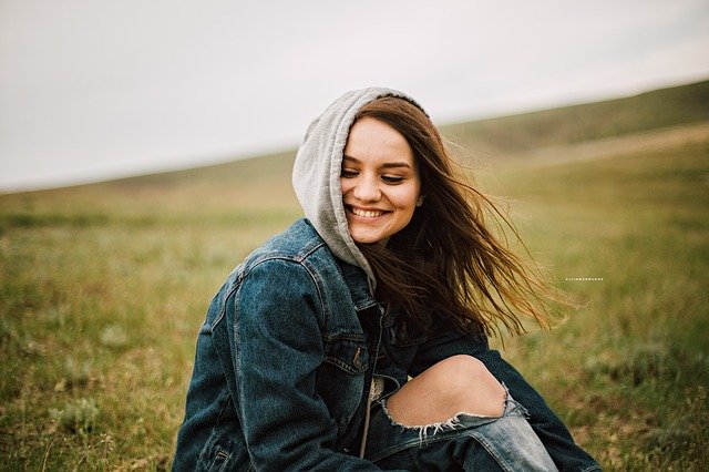 Mujer joven sonriendo en medio de un campo, en la naturaleza